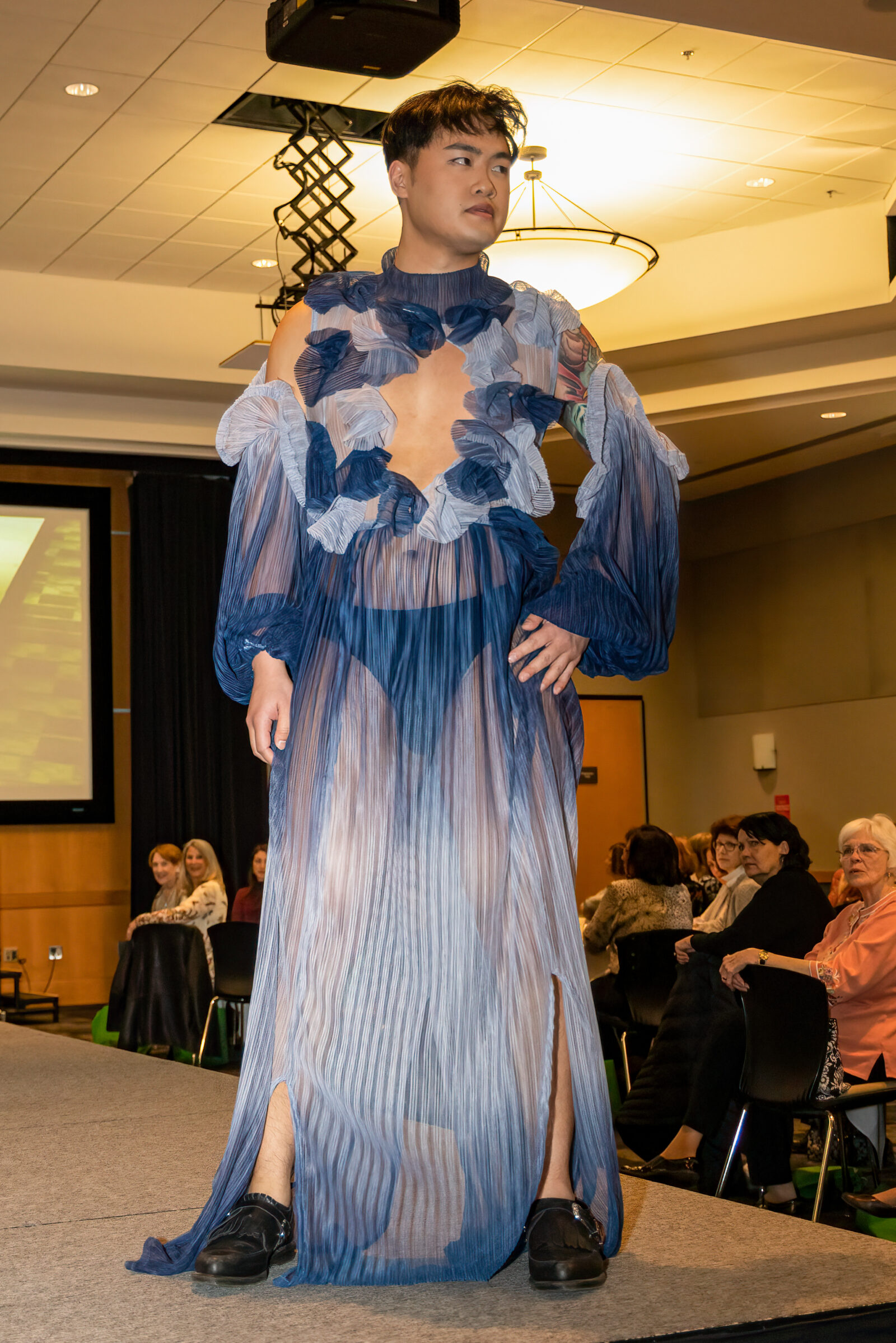 Model in sheer blue ruffled runway gown