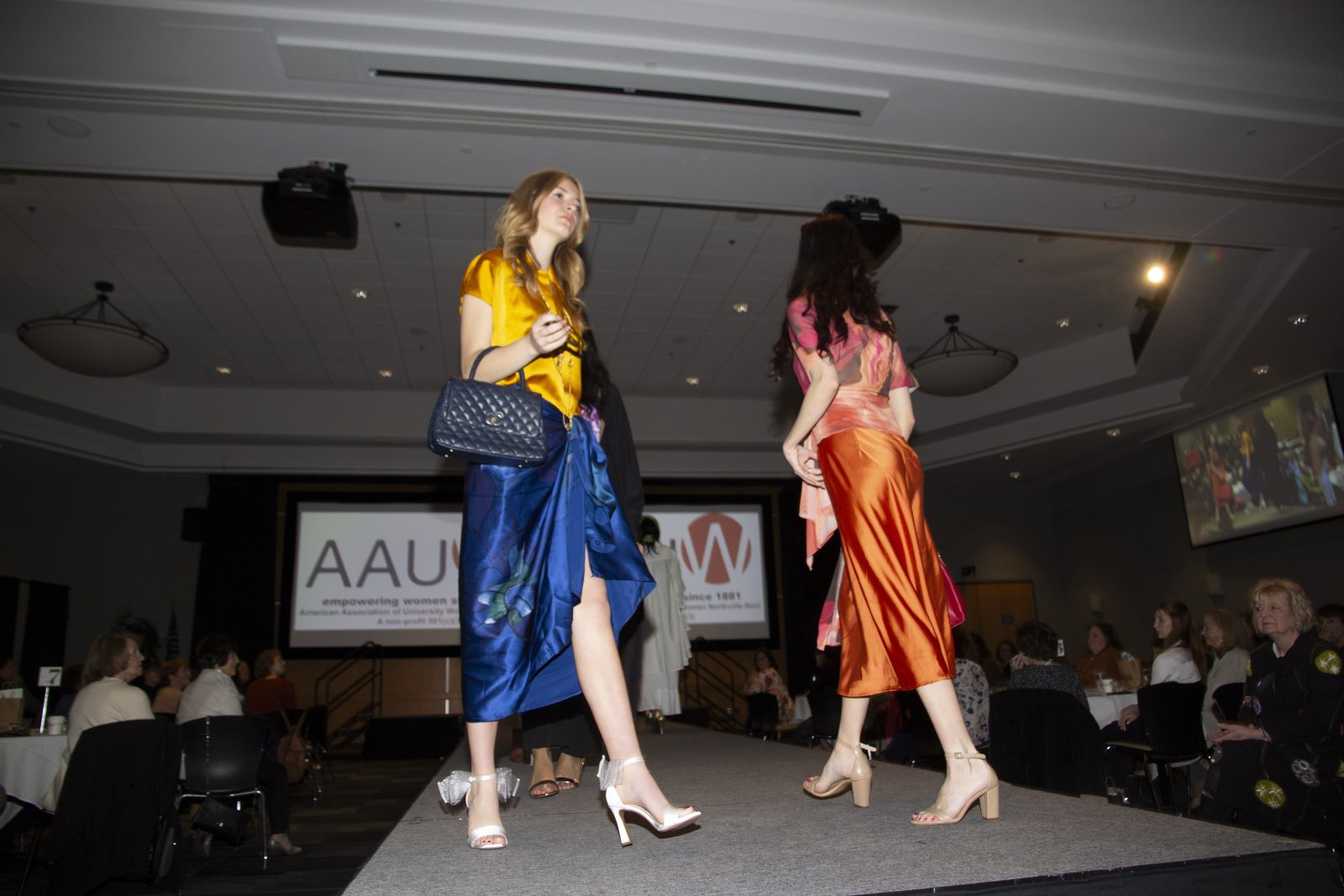 Two models walking runway in colorful satin dresses